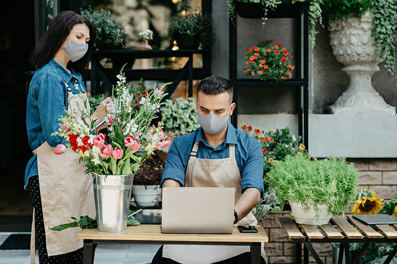 Man and woman in mask, running their flower shop
